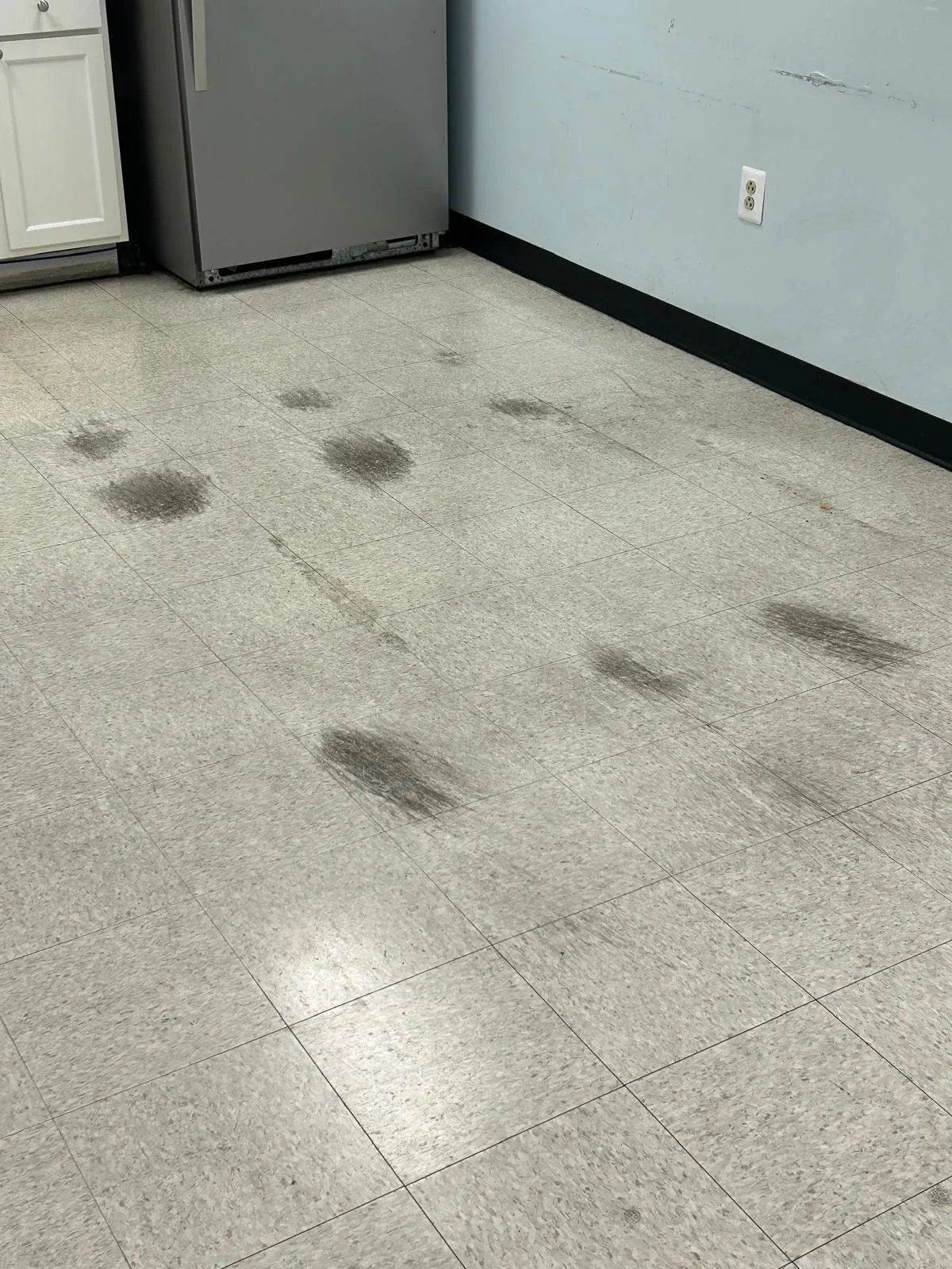 Commercial tile floor before cleaning, with dark scuffs and staining