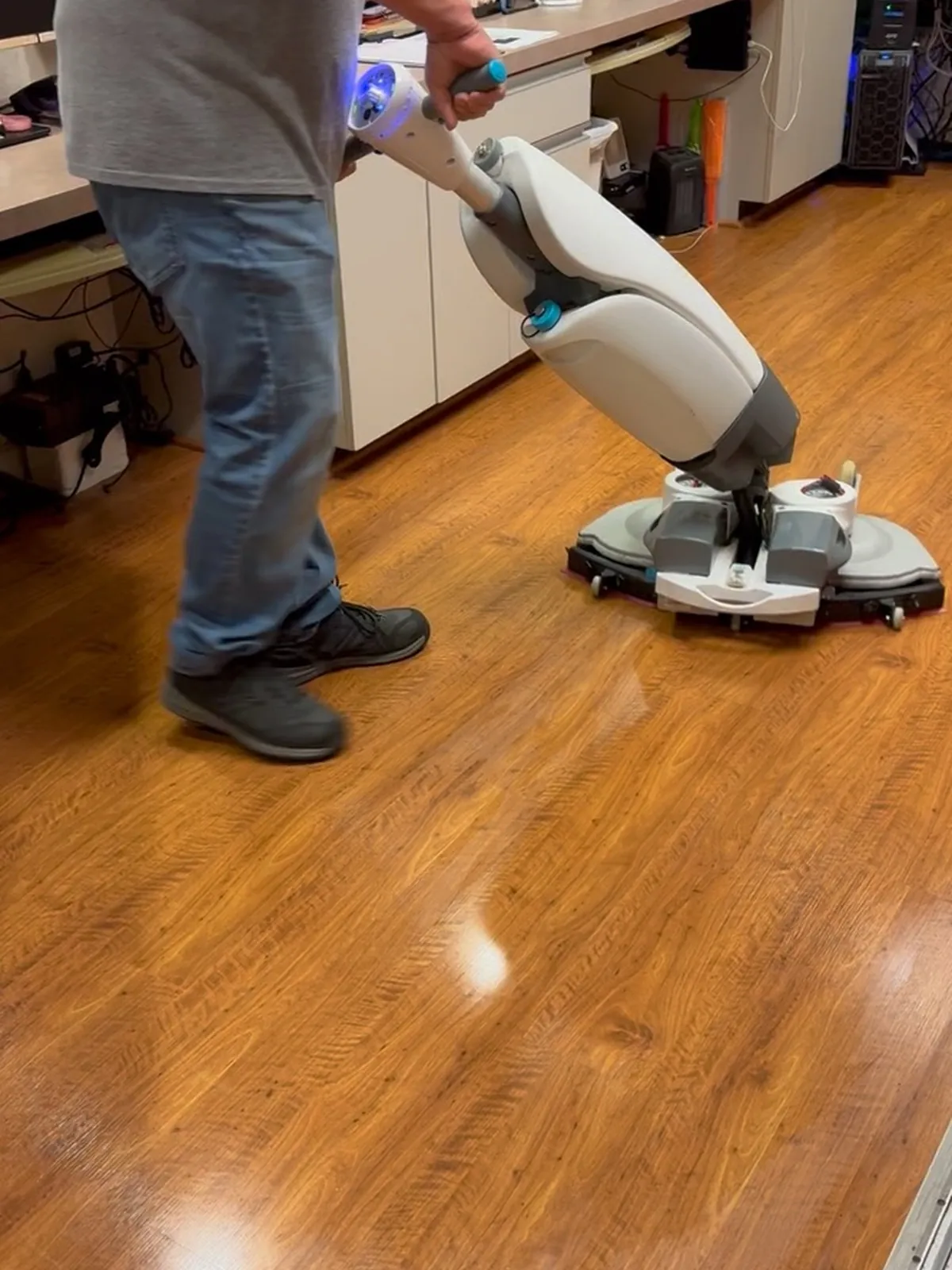 SparkClean crew member running a floor machine on a commercial wood-look floor